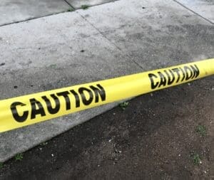 Yellow caution tape across sidewalk and curb