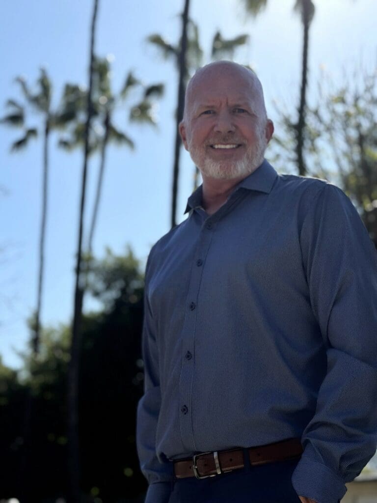 Smiling bald man outdoors with palm trees