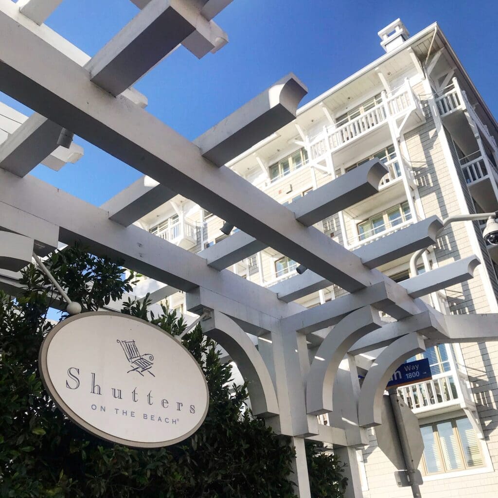 Shutters on the Beach sign with white pergola