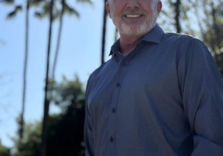 Smiling bald man outdoors with palm trees