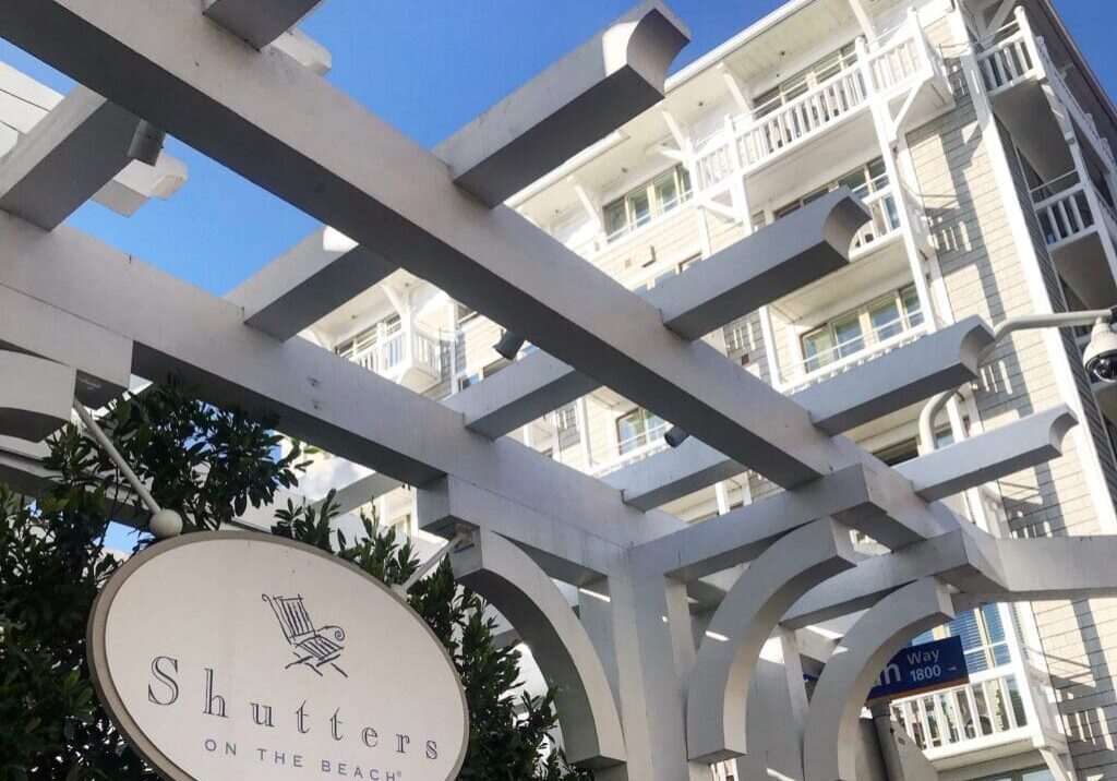 Shutters on the Beach sign with white pergola