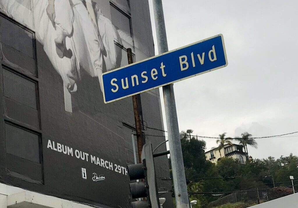 Sunset Blvd street sign with billboard background